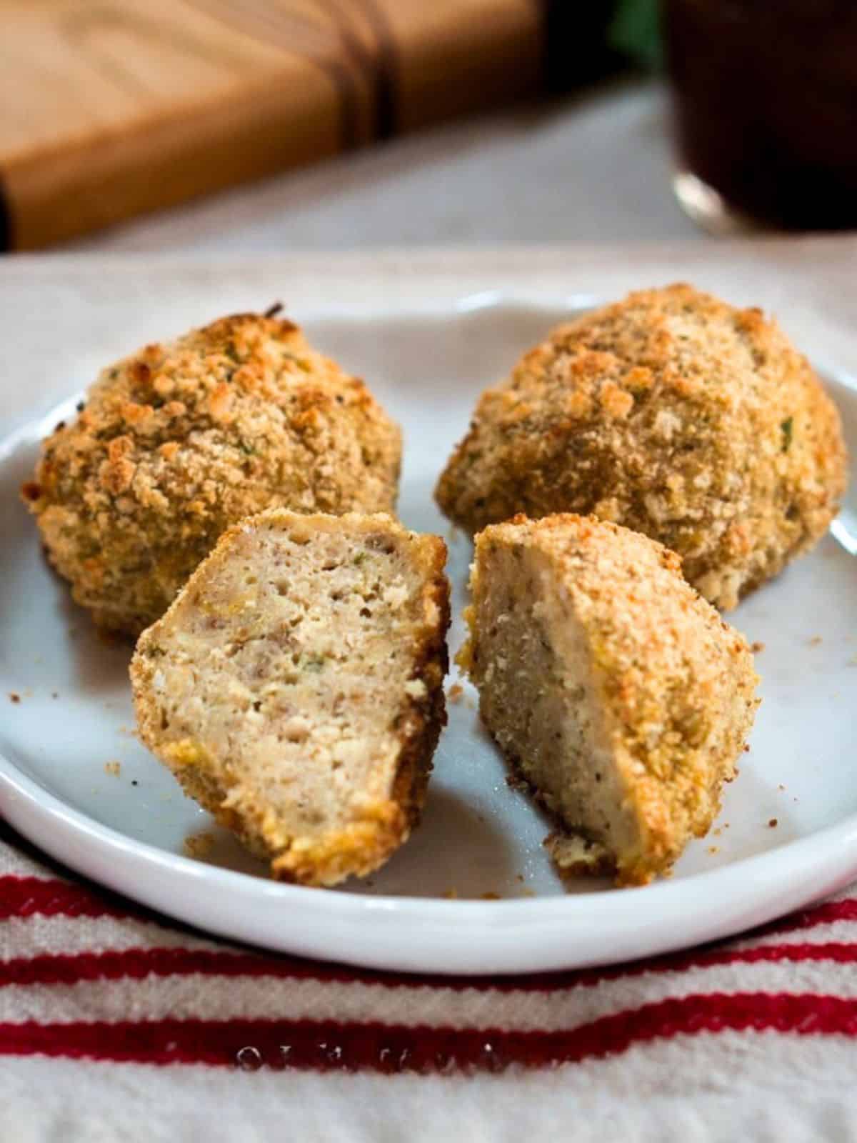 Three meatballs on a plate. The front one is cut in half. Hostess At Heart