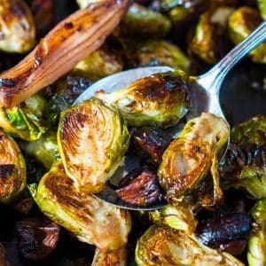 Closeup image of a spoon holding roasted caramelized Brussel Sprouts. Hostess At Heart