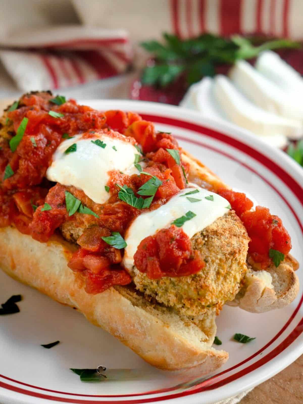 Tableview of a meatball sub sandwich topped with melted mozzarella, marinara, and fresh parsley. Hostess At Heart