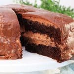 A slice of cake with a chocolate mousse filling being lifted from a round chocolate layer cake. Hostess At Heart