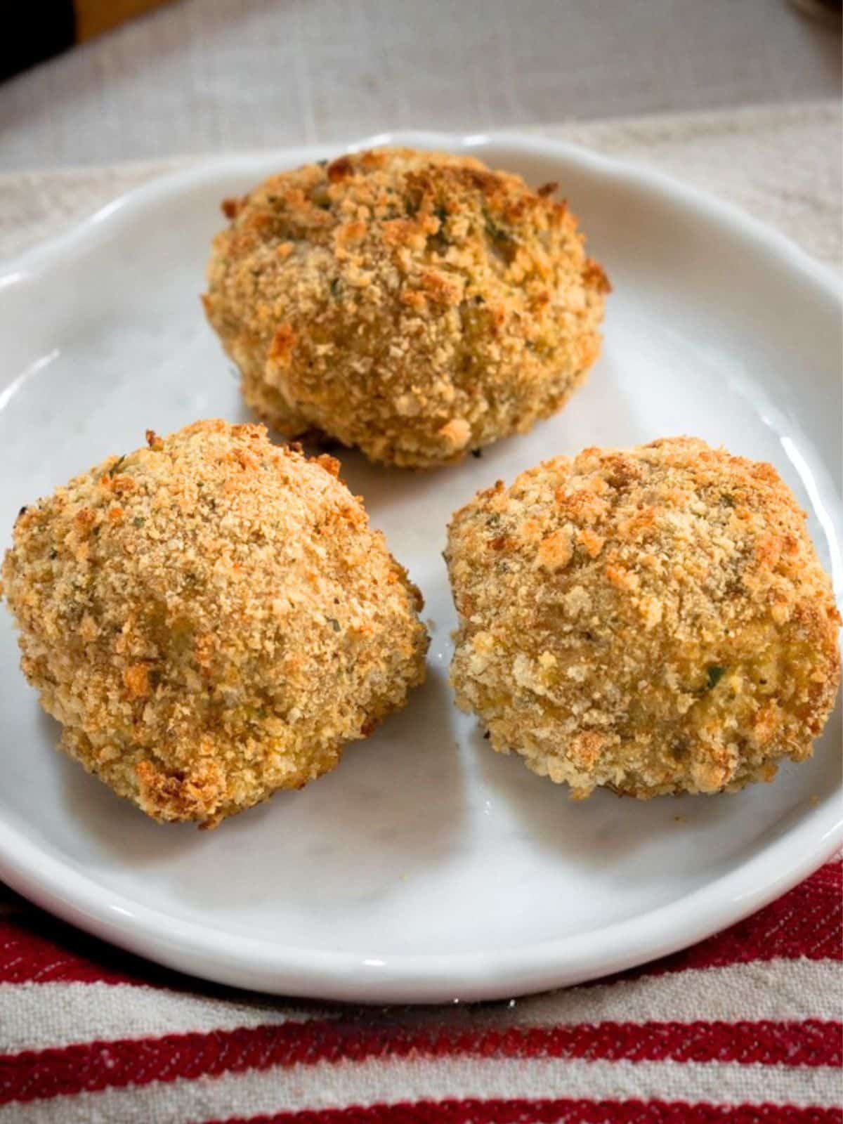 Three baked breaded meatballs on a plate - Hostess At Heart
