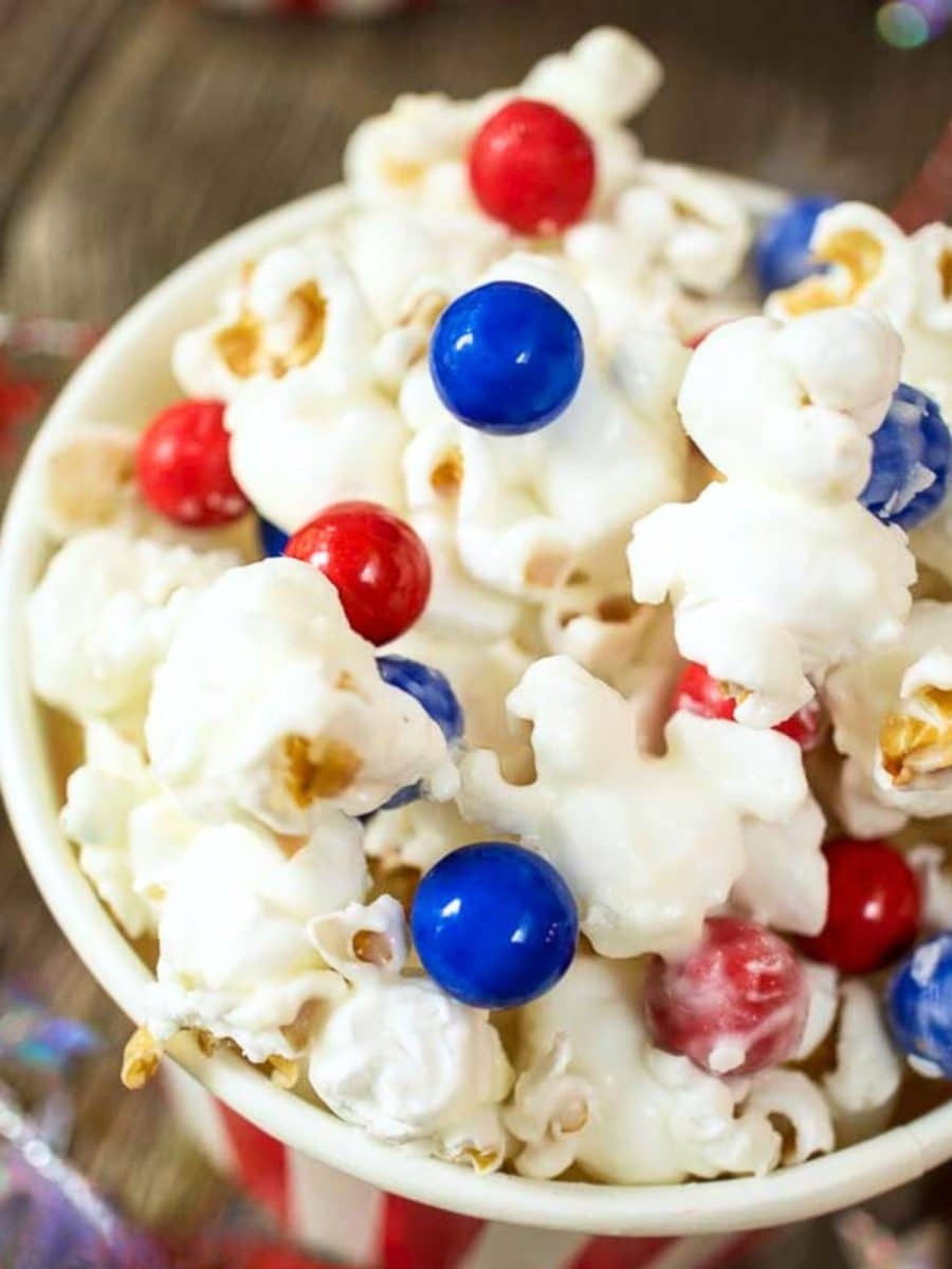 Top down closeup of a cup of candied pop corn decorated with red and blue candy pieces - Hostess At Heart