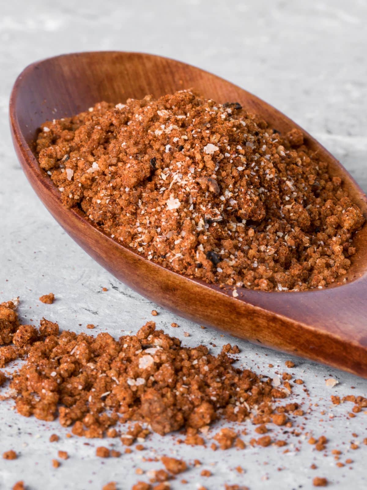 Sideview of a wooden spoon filled with homemade spice rub - Hostess At Heart