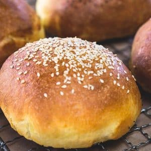 Sideview of a golden brown hamburger bun topped with sesame seeds. Hostess At Heart