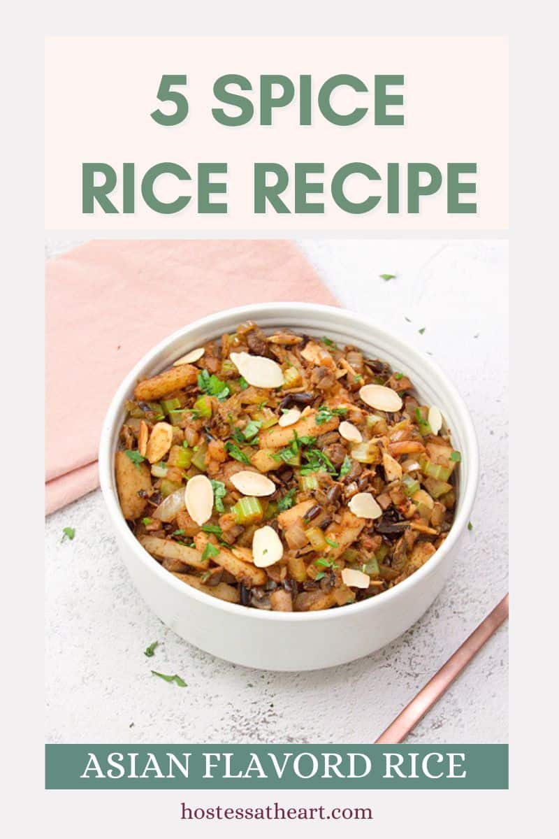 An image for Pinterest of Top down view of a white bowl filled with cooked wild rice, celery, onion, mushrooms, chestnuts, and spices. It's Garnished with sliced almonds and parsley. Hostess At Heart