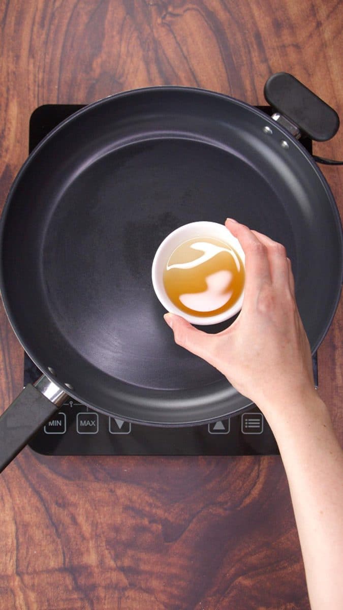 A dish of sesame oil being added to a skillet. Hostess At Heart