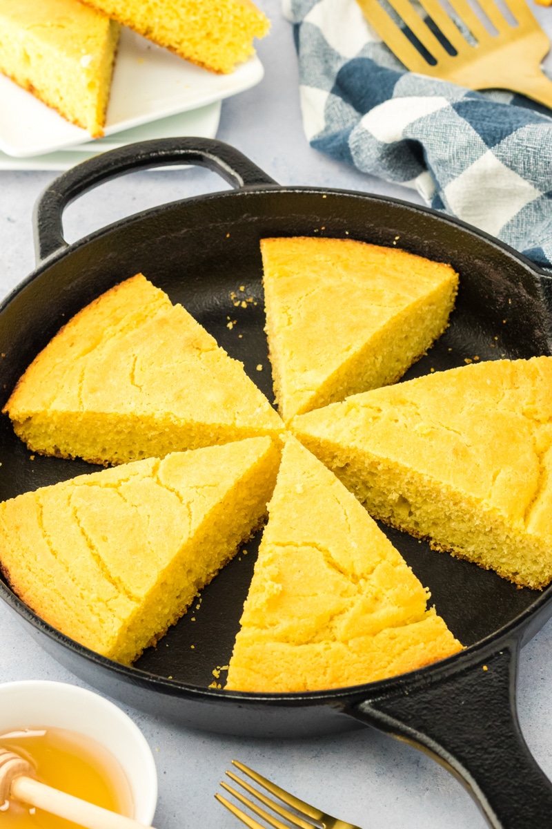 A cast iron containing 5 wedges of baked corn bread. Hostess At Heart