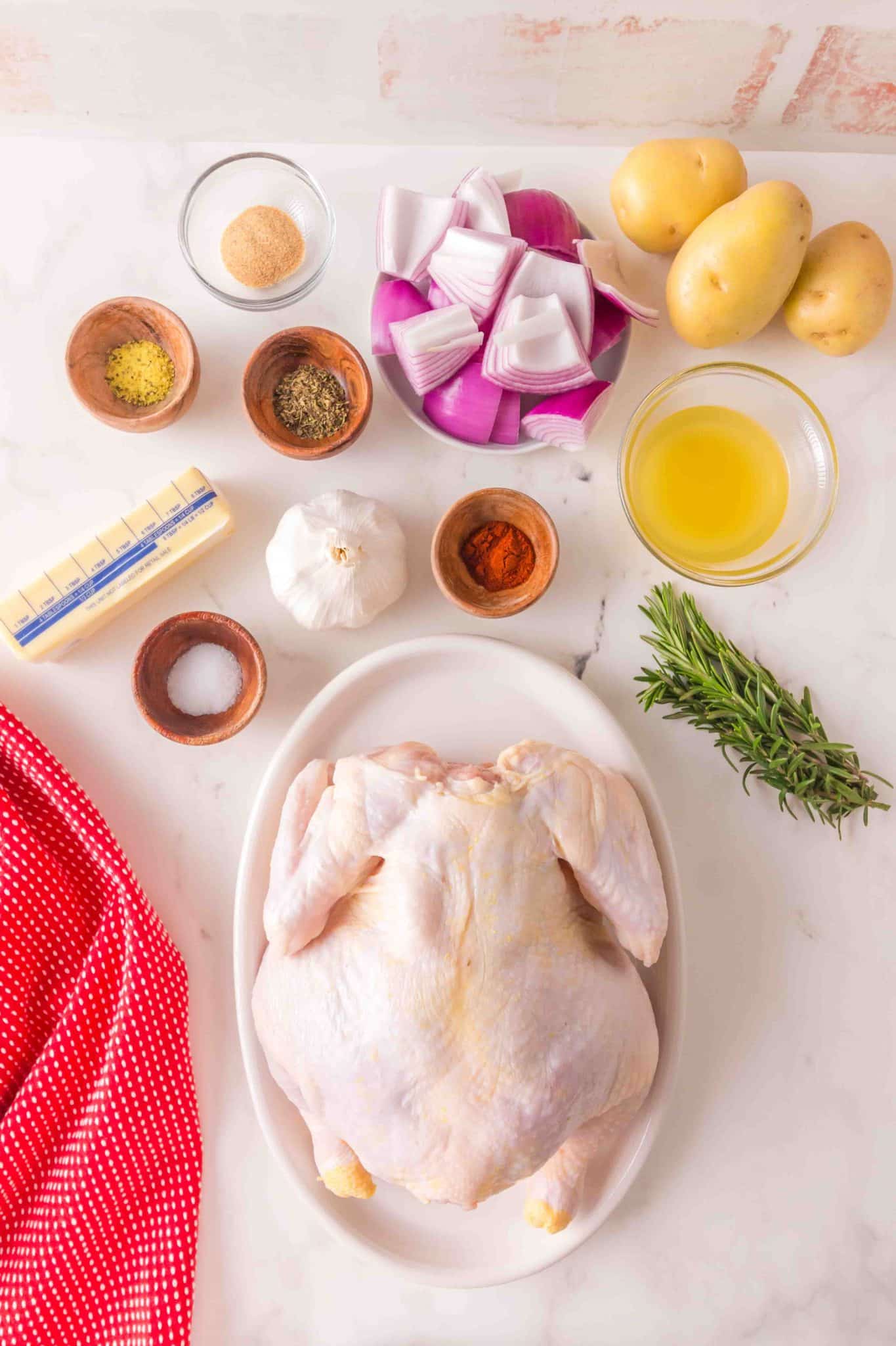 Ingredients: lemon pepper, garlic powder, Italian seasoning, red onions, potatoes, butter, garlic cloves, paprika, oil, rosemary, salt, and a whole chicken.