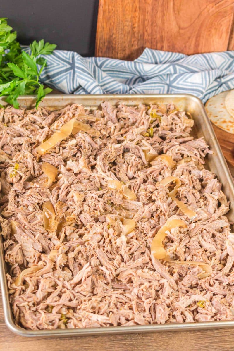 Shredded pork Carnitas filling with onions sitting in a baking sheet prepared to be roasted crispy - Hostess At Heart