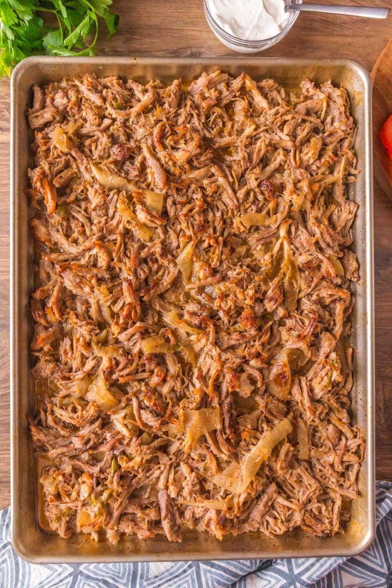 A baking sheet filled with roasted carnitas pork and onion slices. Hostess At Heart