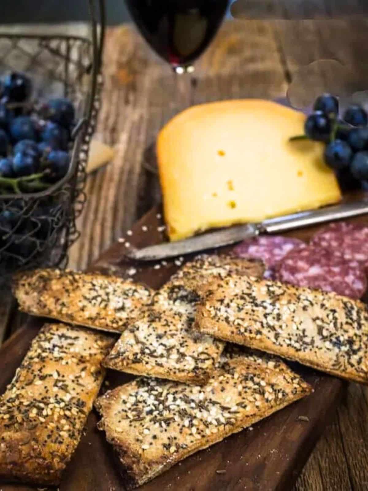 A cutting board holding homemade seeded crackers and a block of Gouda cheese. Hostess At Heart