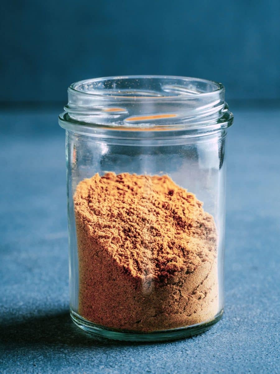 A sideview of a spice jar filled with homemade creole seasoning. Hostess At Heart
