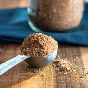 Sideview of a measuring spoon overflowing with a homemade Creole Spice Mix - Hostess At Heart