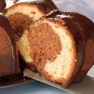 A side image of a Hersheys syrup cake with a slice being lifted from the whole cake showing the two tone crumb - Hostess At Heart