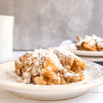 A sideview of a serving of baked french toast dusted with powdered sugar. Hostess At Heart