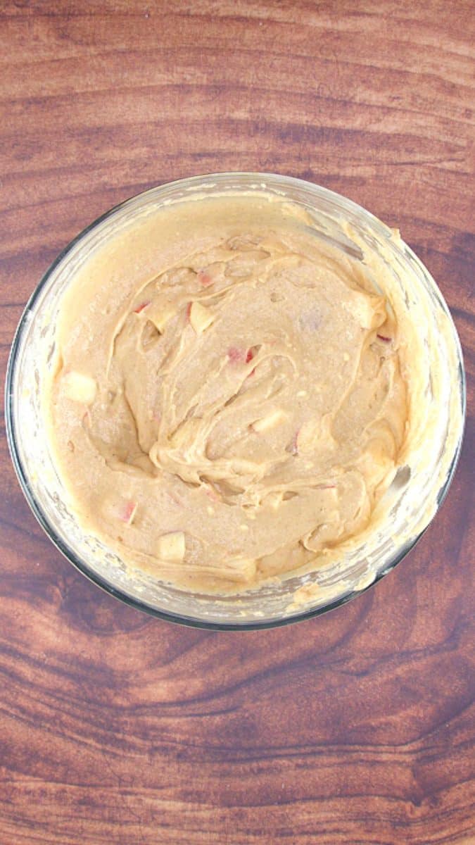 A mixing bowl filled with cake batter filled with diced apples - Hostess At Heart