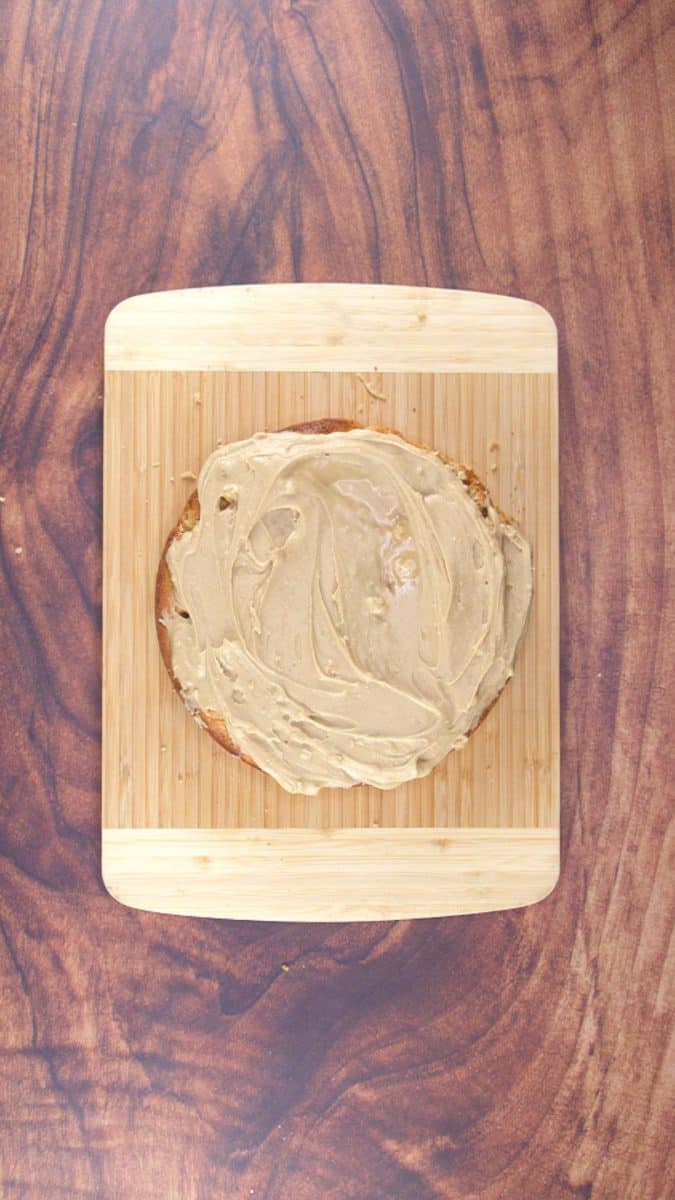 The top of the bottom layer of a apple caramel cake topped with frosting.