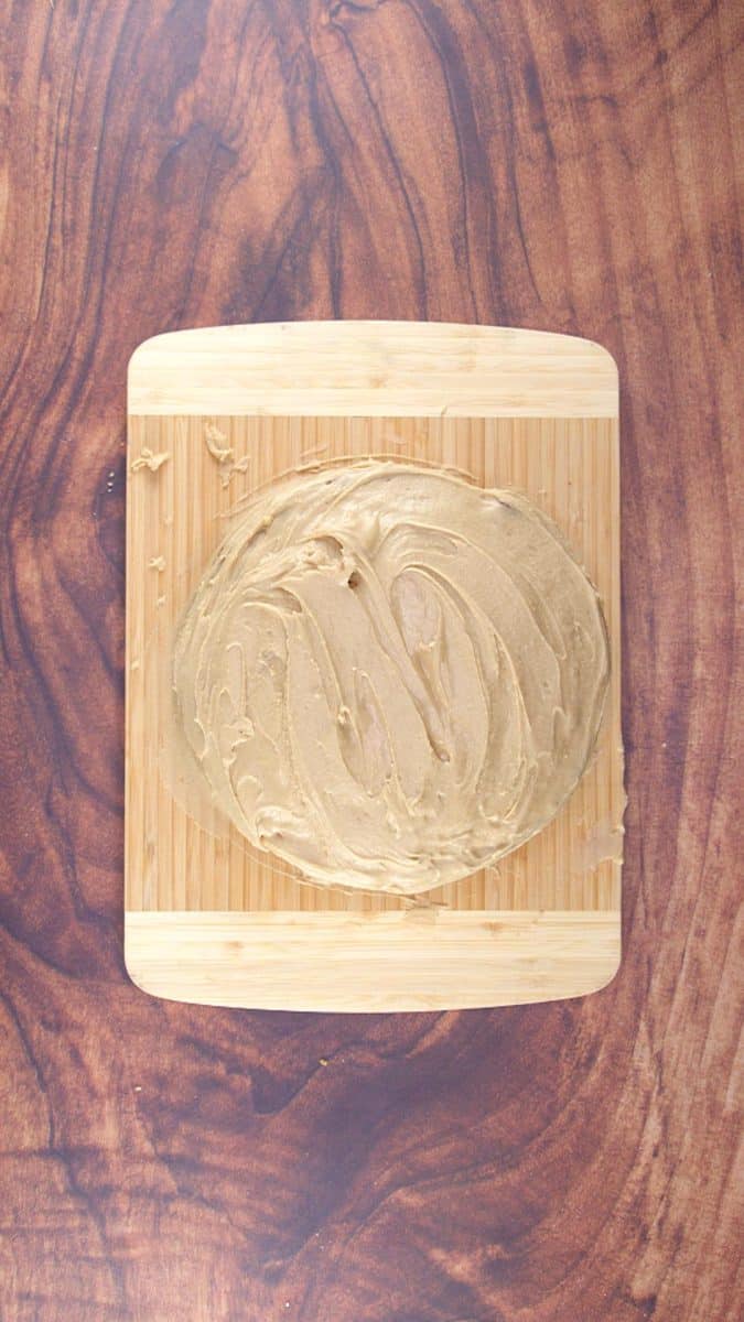 Top down view of a frosted layer cake sitting on a cutting board - Hostess At Heart
