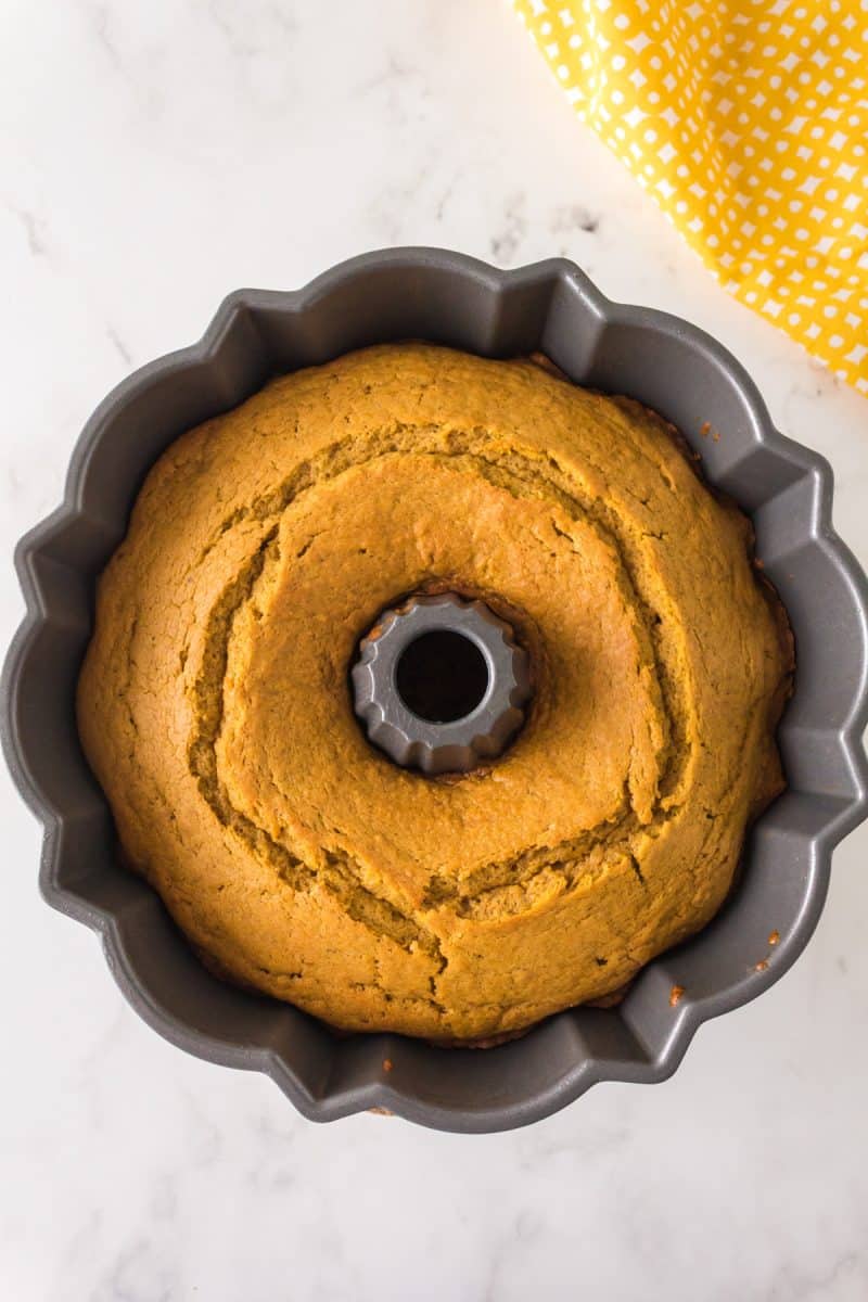 Top down view of a baked bundt cake in the pan showing normal cracks in the surface. Hostess At Heart