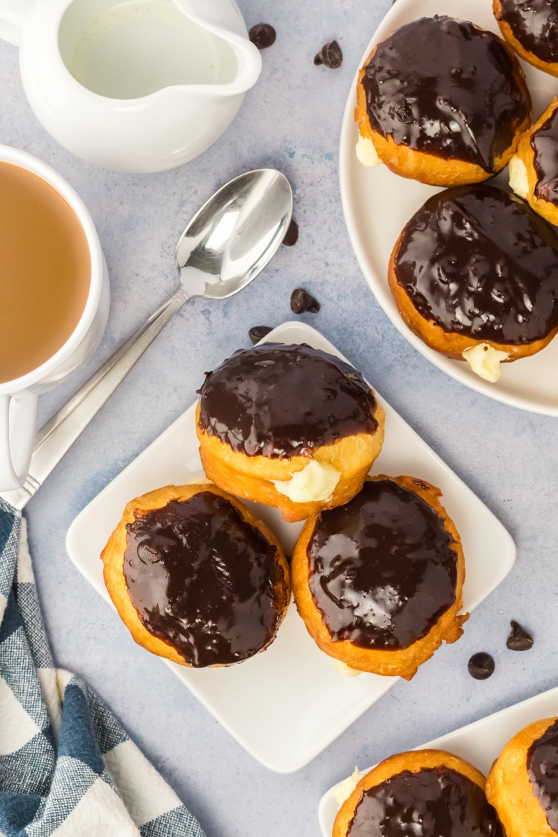 Top down view of three chocolate covered doughnuts oozing with a cream filling on a plate. Hostess At Heart