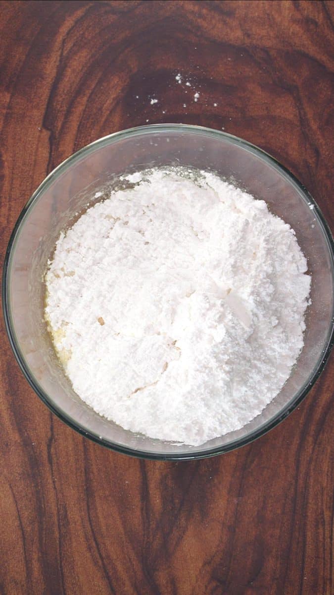 Confectioners sugar added to a bowl of whipped butter for frosting recipe - Hostess At Heart