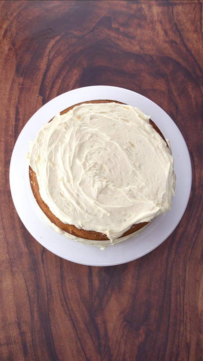 Top down view of a round vanilla layer cake with the second layer topping the first with frosting - Hostess At Heart