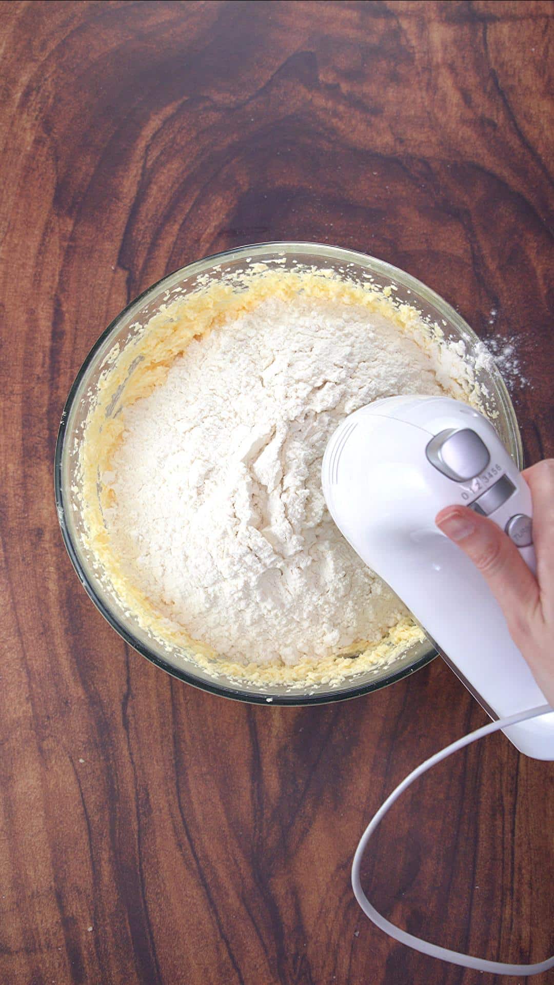 A mixer beating dry birthday cake ingredients into wet ingredients. Hostess At Heart