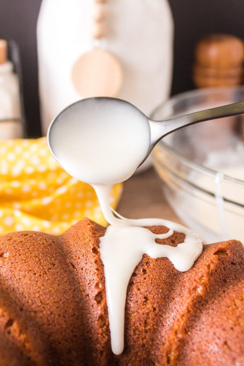 A spoon applying glaze to a bundt cake. Hostess At Heart