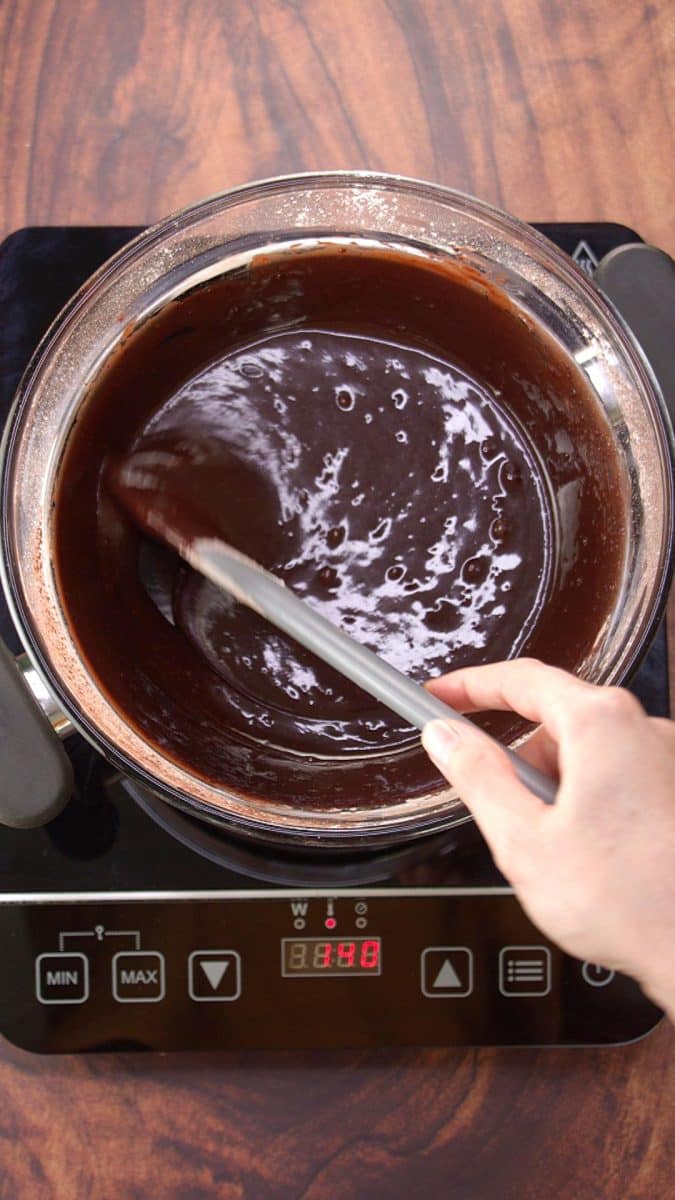 Smooth chocolate frosting glaze mixed smoothly over a heated pan of water. Hostess At Heart