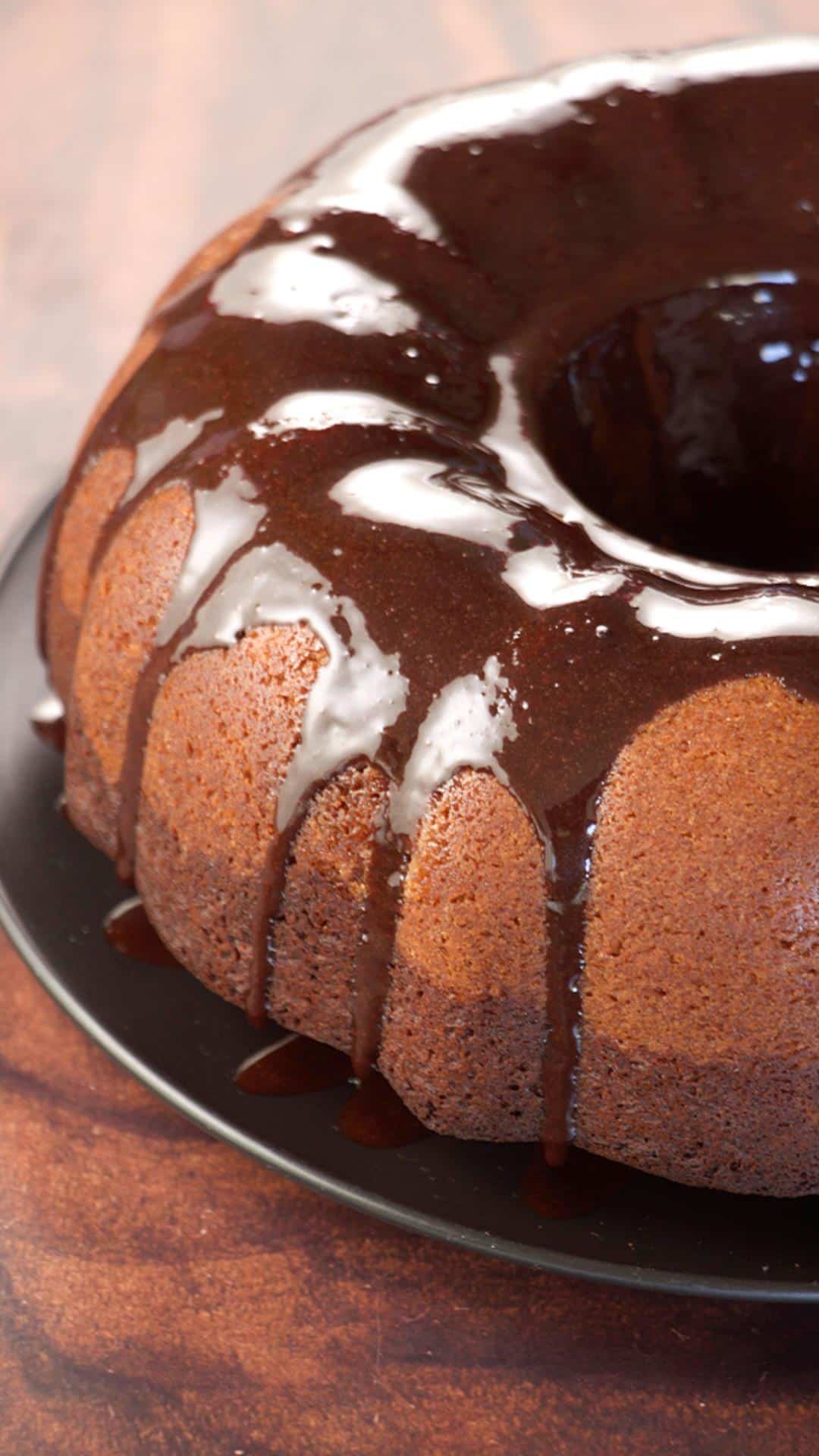 Angled view of a chocolate glaze running down the side of a chocolate syrup bundt cake - Hostess At Heart