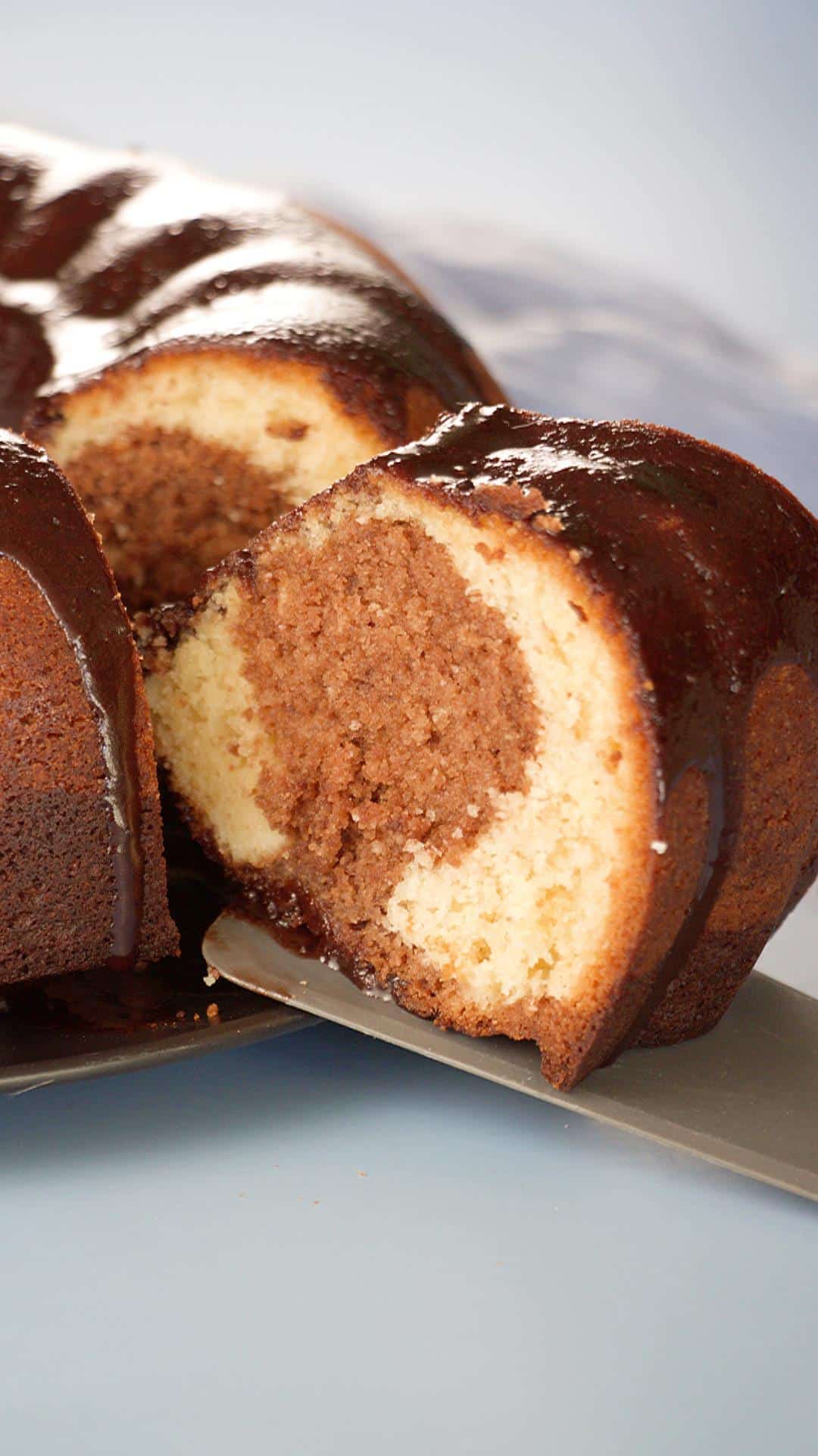 A slice of Hersheys syrup cake being removed from the whole cake with a spatula - Hostess At Heart