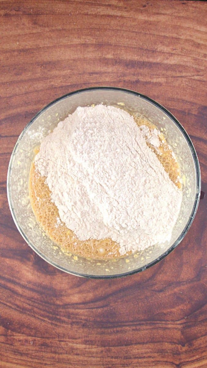Dry ingredients added to wet apple cake batter in a mixing bowl - Hostess At Heart