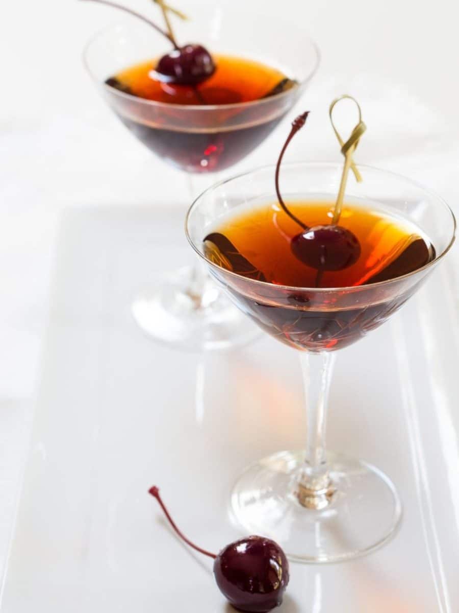 Angled sideview of two cocktail glasses filled with manhattan cocktails made with rum - Hostess At Heart