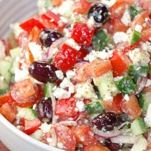 A bowl filled with a vegetarian salad: Tomatoes, cucumbers, kalmata olives, red onion and Feta. A vinaigrette dressed the salad.