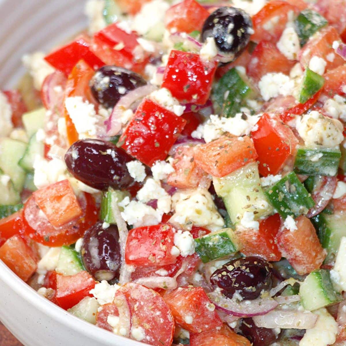 A bowl filled with a vegetarian salad: Tomatoes, cucumbers, kalmata olives, red onion and Feta. A vinaigrette dressed the salad.