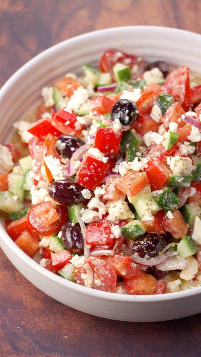 Close up vertical image of the Mediterranean Cucumber Tomato
Salad in a white bowl.