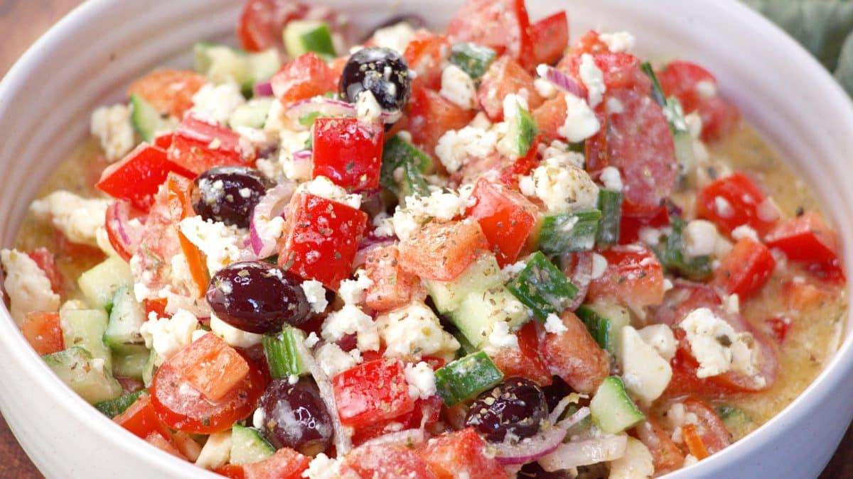 Close up horizontal image of  iMediterranean Cucumber Tomato
Salad in a white bowl.