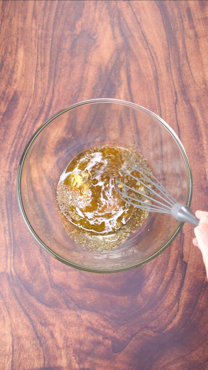 Mixing the Mediterranean Salad Dressing in a glass bowl with a whisk.