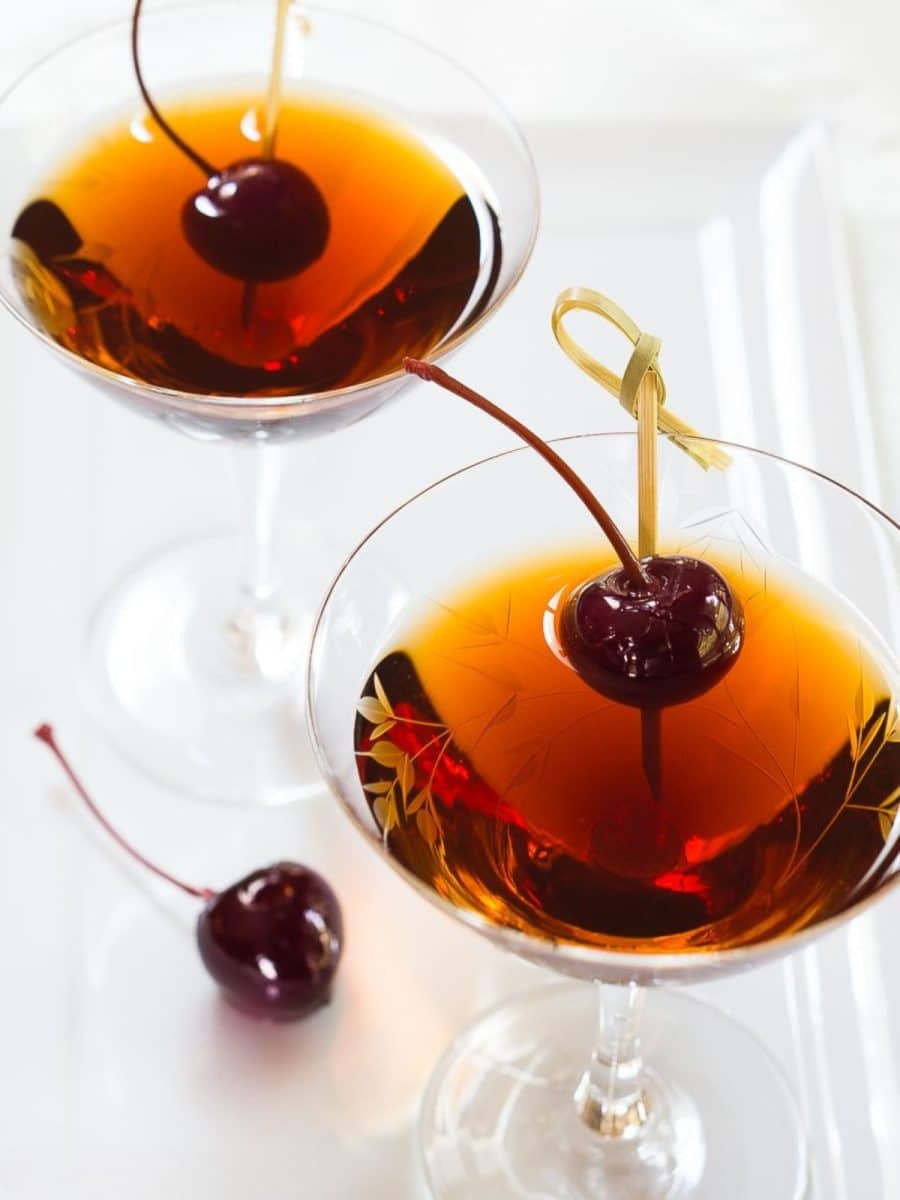 Angled view of two rum manhattan cocktails garnished with bada cherries - Hostess At Heart