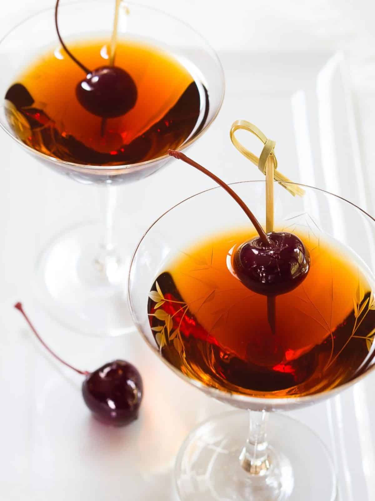 Angled view of two rum manhattan cocktails garnished with bada cherries - Hostess At Heart