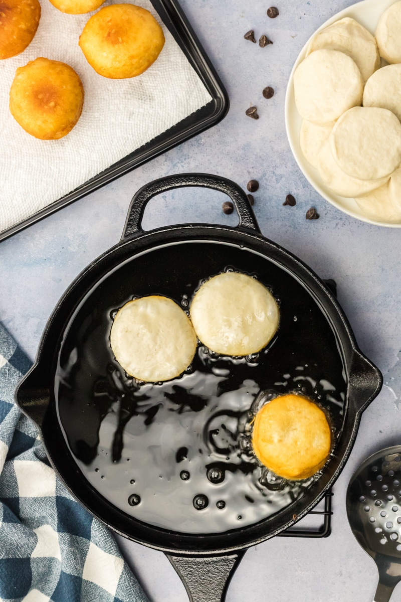 Top down view of a biscuits frying in a cast-iron skillet. Hostess At Heart