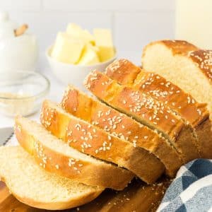 Sideview of a loaf of sesame bread that's been sliced and the slices are fanned out on a cutting board. Hostess At Heart