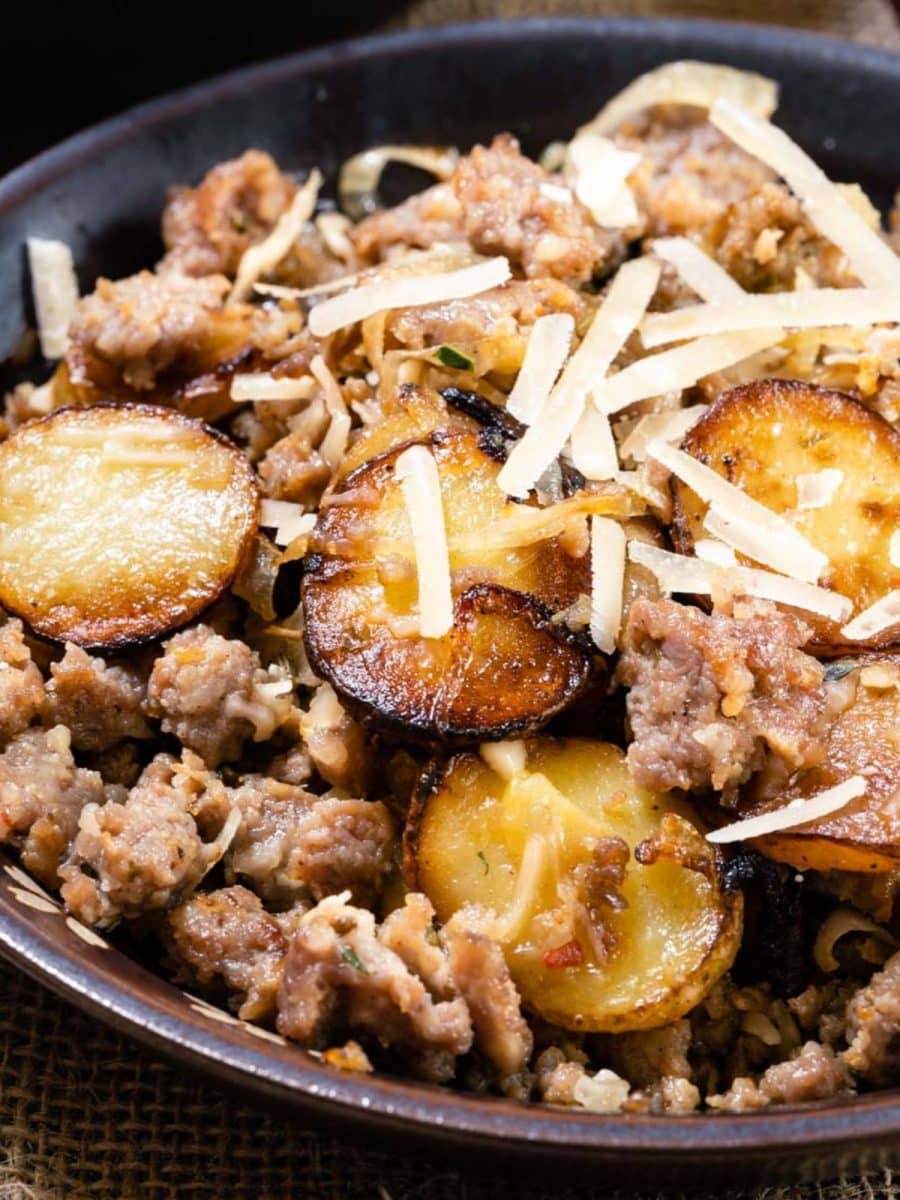 Closeup view of a bowl of ground sausage with fried potatoes and onions garnished with cheese - Hostess At Heart