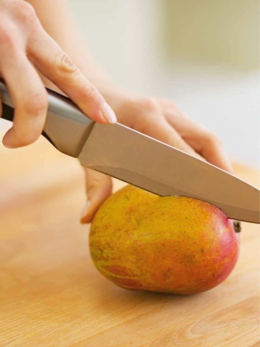 An image showing how to set a mango on it's side and slicing it. Hostess At Heart