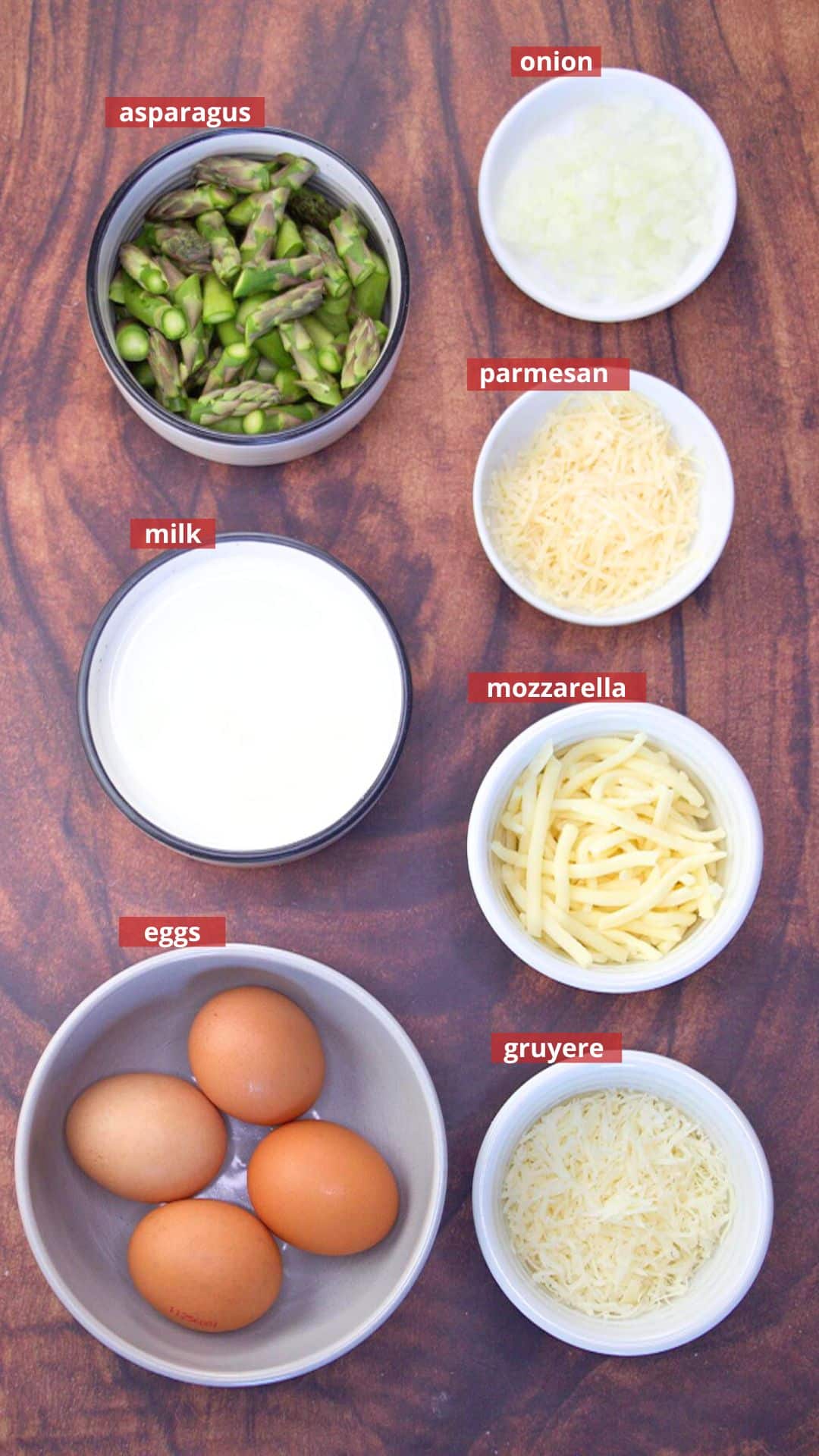 Ingredients used to make cheese crustless asparagus quiche including eggs, cheese, asparagus, milk, and onion. Hostess At Heart