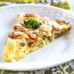 Front view of a slice of asparagus crustless quiche topped with cheese. Hostess At Heart