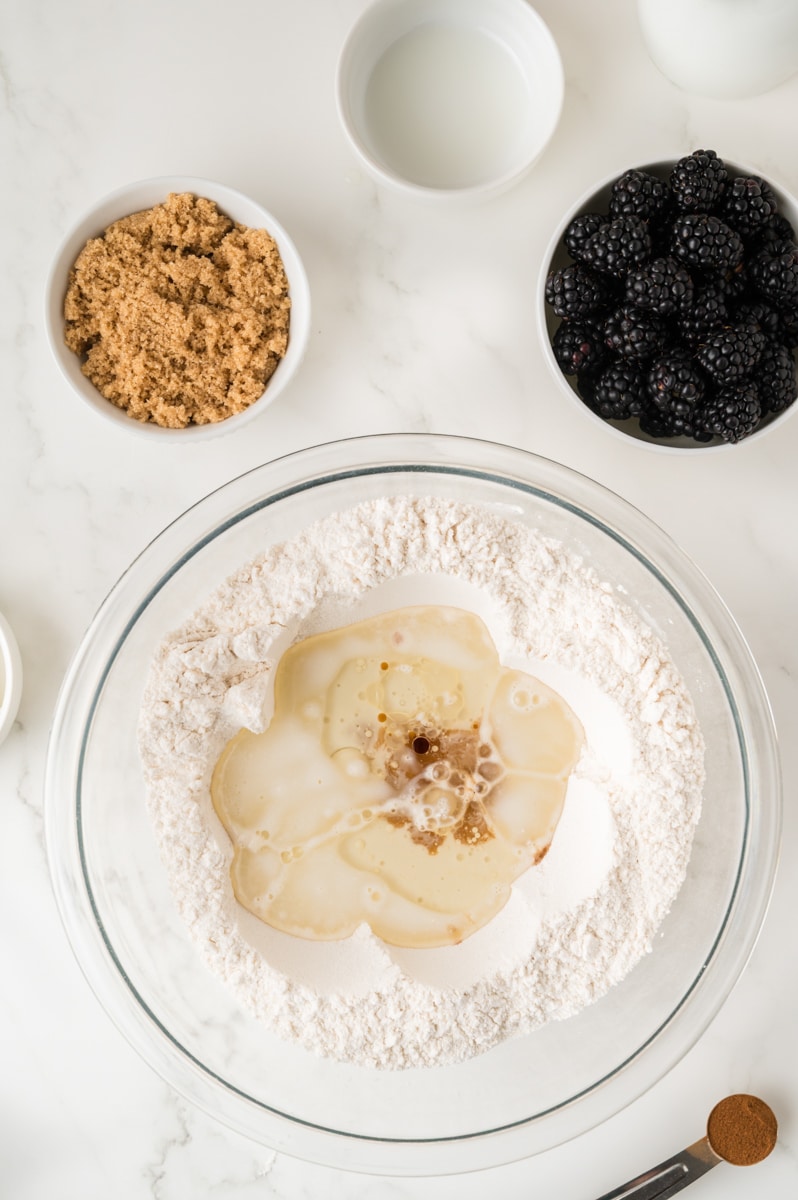 Dry ingredients in a mixing bowl with liquids being added to the top.