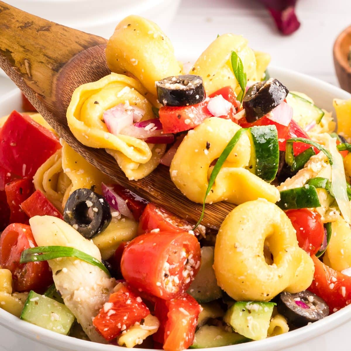 Closeup view of a wooden spoon filled tortellini pasta salad - Hostess At Heart