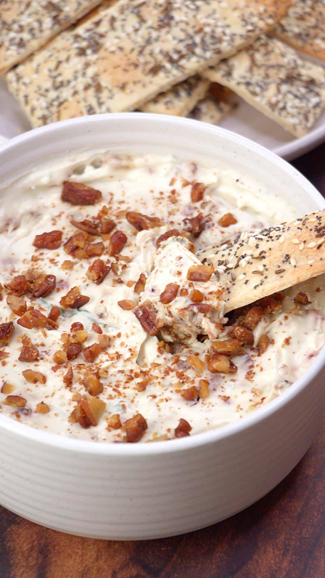 Close up of Gorgonzola dip in a white bowl with crackers in the background.