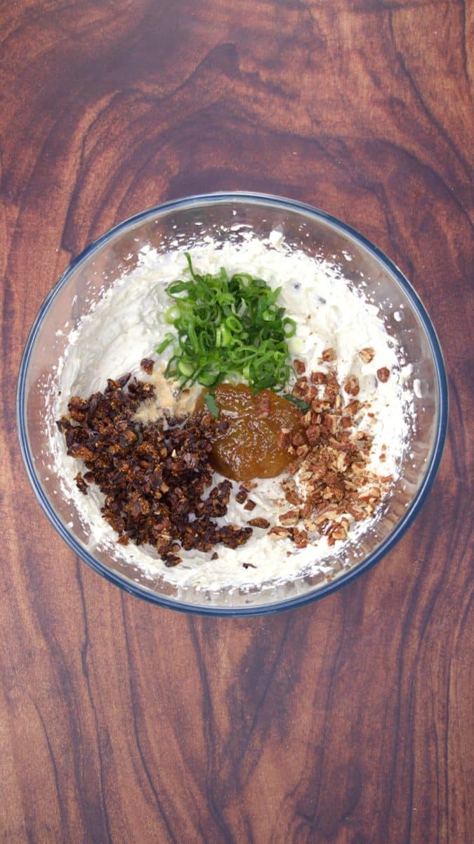 Top down view of herbs, figs, fig jam, and pecans added to a bowl of blended cheeses - Hostess At Heart